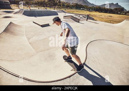Skater, sports and man at skate park in city performing action trick or stunt. Fitness, skateboarding and young male skateboarder on ramp training Stock Photo