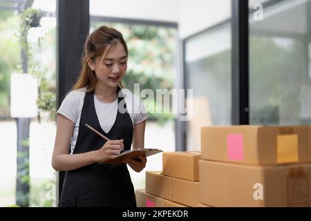 business woman checking customer order online shipping boxes at home. Starting Small business entrepreneur SME freelance. Online business, Work at Stock Photo