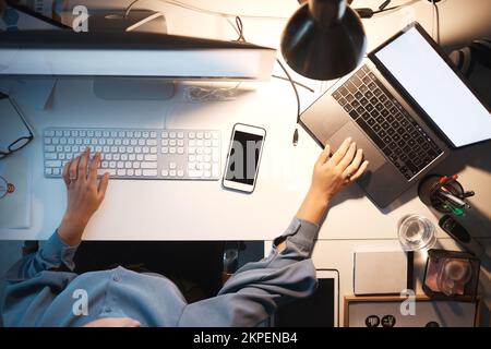 Business woman, computer and hands typing on keyboard above at night with laptop, PC and phone on office desk for software, coding and engineering. IT Stock Photo