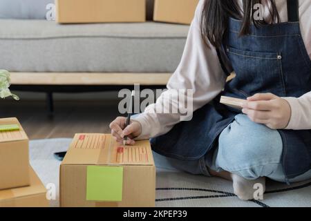 Starting small businesses SME owners woman entrepreneurs working, box and check online orders to prepare to pack the boxes, sell to customers, sme Stock Photo