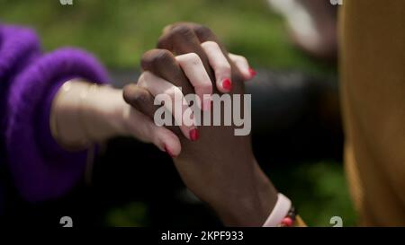 Ethnically diverse couple holding hands close-up. Mixed race woman and black man showing love and affection Stock Photo