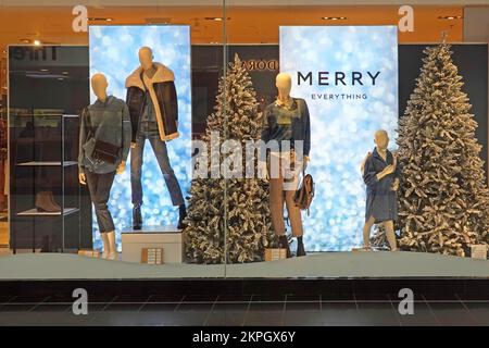 Next plc retail business store close up part of Christmas tree & Merry Everything shop window display promoting fashion clothing mannequins England UK Stock Photo
