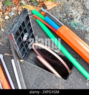 Fibre optic broadband discarded random cable offcuts beside open consumer junction box for illustration & connected customer cable ready if wanted UK Stock Photo