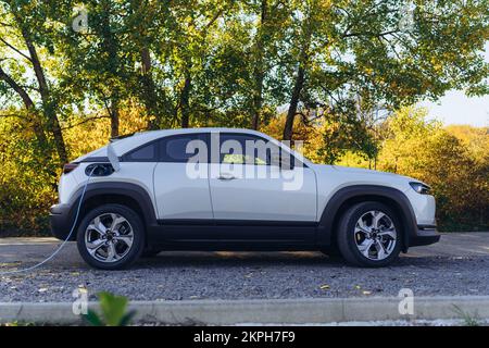 Charging an electric car in home,sustainable transportation concept. Stock Photo