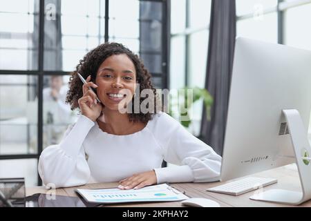Waist up portrait of cheerful young mixed race female with curly hair Stock Photo