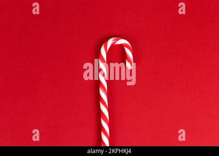 Red minimalistic christmas background with a candy cane top view with copy space. Stock Photo