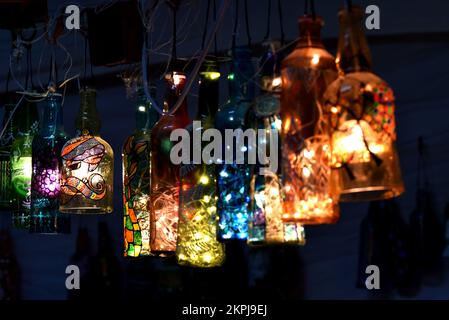 Hanging lights made out of discarded bottles. Home decor with painted bottle art and craft. Stock Photo