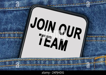 Business and finance concept. In a pocket of jeans there is a smartphone on the screen of which the text - JOIN OUR TEAM Stock Photo