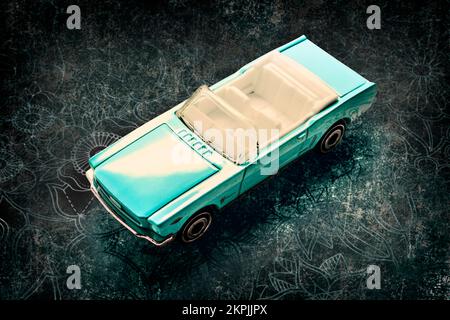 Automotive art on a toy ’65 Ford Mustang Convertible on decorative floral backdrop. Blue classics Stock Photo