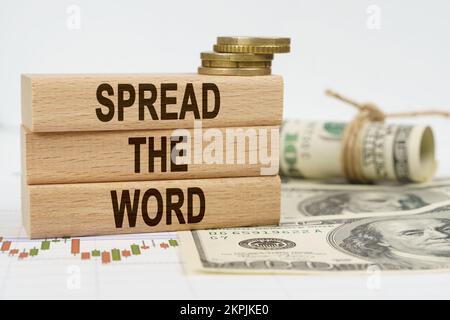 Business and finance concept. On the table are dollars, financial charts and wooden plates on which it is written - SPREAD THE WORD Stock Photo
