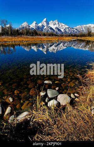 Tetons Tetons Mountain Range in Winter with snow and trees and reflection of light in River Stock Photo