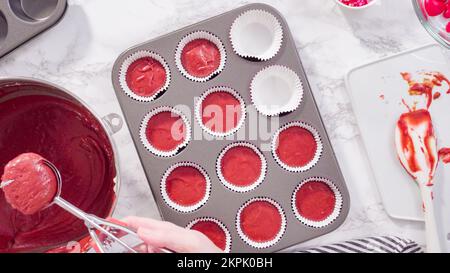 Scooping cupcake batter with a dough scoop into cupcake foil liners to bake  gingerbread cupcakes Stock Photo - Alamy