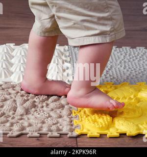 Baby toddler foots close-up on a medical orthopedic mat. Child legs with flat feet on a medical rug. Kid aged one year four months Stock Photo