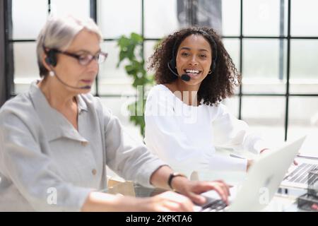 Young friendly operator woman agent with headsets working in a call centre. Stock Photo