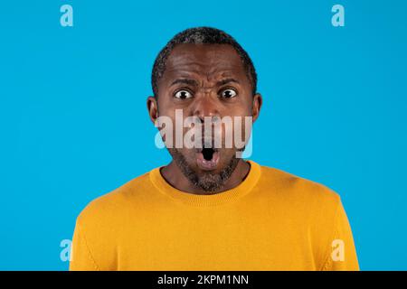 Shocked mature african american man looking at camera on blue Stock Photo