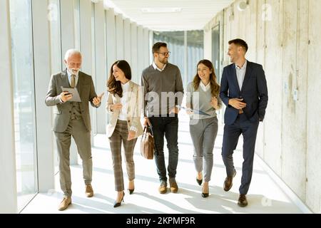 Group of corporate business professionals walking through office corridor on a sunny day Stock Photo