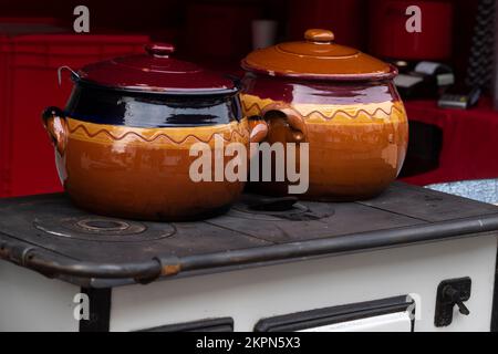 Retro ceramic pots placed on an old vintage stove for outdoor cooking in Eastern Europe Stock Photo