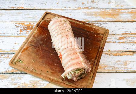 Preparation of a porchetta with a mixture of aromatic herbs placed on a piece of fresh pork belly open in the thickness Stock Photo