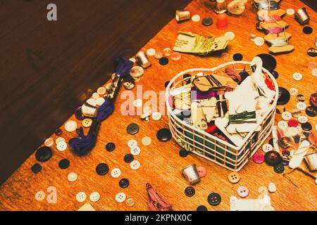 Rustic old-fashion scene on a messy mix of textile threads with mixed buttons and thimbles. Crafting corner Stock Photo