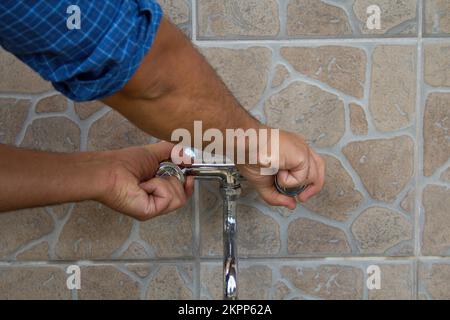 Image of a man's hands turning off the water tap. Saving and safeguarding the waste of water.