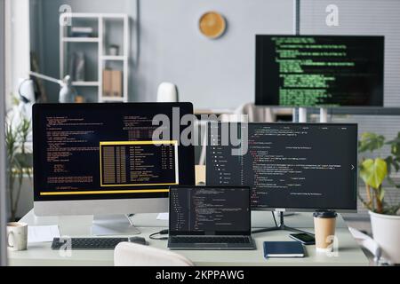 Computers and laptop with programming code in empty office of IT company Stock Photo