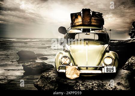 Vintage 1960 VW Beetle on a rocky Australian landscape coast packed to the rafters with vintage luggage. The travel bug Stock Photo