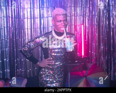 Non-binary person drinking happily at a party Stock Photo