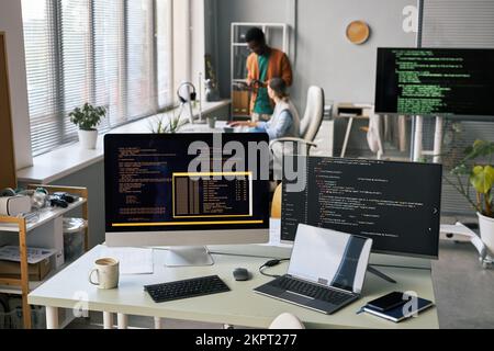 Computers and laptop with programing code on desk of software developer Stock Photo