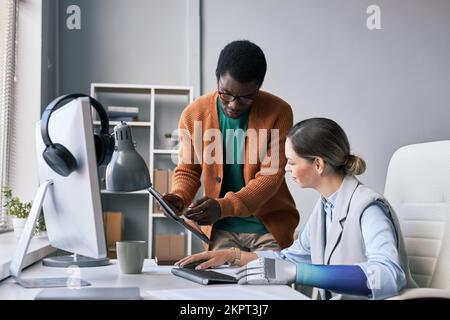 Project manager asking colleague to help him with fixing software bug Stock Photo