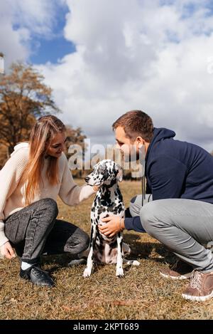 Couple plays with his Dalmatian dog on walking in park Stock Photo