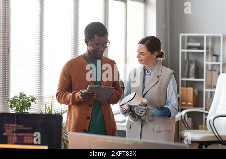 Smiling developer asking woman with prosthetic arm to wear VR headset for testing new application he created Stock Photo