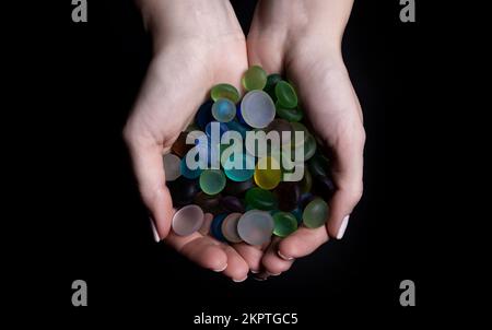 hands with colored stones Young woman is holding a collection of various raw mineral gemstones in her palm isolated on black background Stock Photo