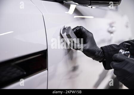 employee of a car wash or a car detailing studio applies a ceramic coating Stock Photo