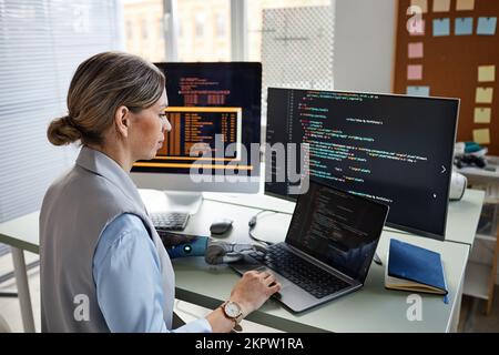 Young female progammer checking code on laptop screen Stock Photo