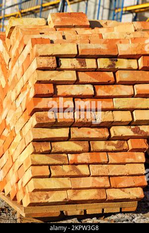Orange brick stacked with a stack on a wooden pallet. Stock Photo
