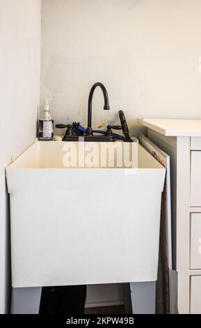 A small laundry room sink in the corner of a new construction laundry room Stock Photo