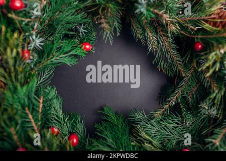 Christmas and New Year wreath made of fir, pine, evergreen branches, cones decorated with berries. Space Stock Photo