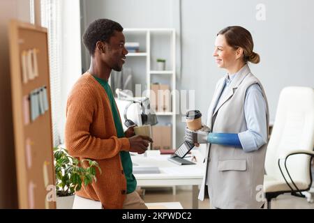 Cheerful business people drinking coffee and discussing plans for the day Stock Photo
