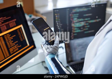 Closeup image of software developer with prosthetic arm testing code on smartphone Stock Photo