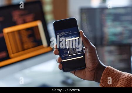 Hand of developer showing programming code on smartphone screen Stock Photo