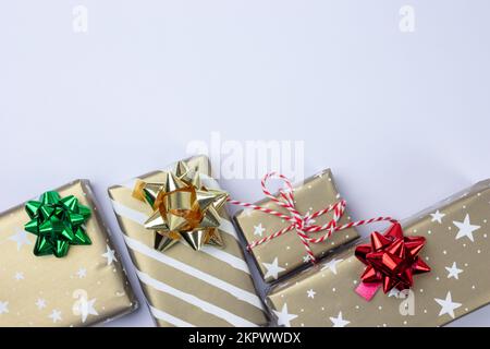 Presents and gift boxes with copy space on white background top view, craft wrapping with stars and stripes, silver, red and green bow. Stock Photo