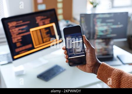 Hand of developer showing smartphone with code of new app on screen Stock Photo