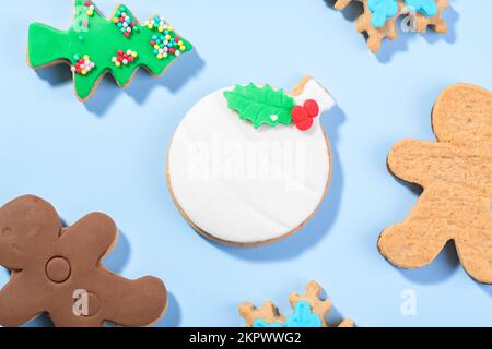 Christmas cookies shape of ball, gingerbread man and candy cane form on the blue background, top view, flat lay Stock Photo
