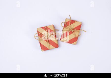 Two craft paper presents or gift boxes in red and brown organic rustic packaging on white background top view copy space. Stock Photo