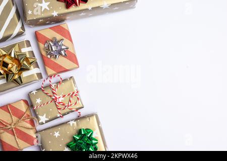 Presents and gift boxes with copy space on white background top view, craft wrapping with stars and stripes, silver, red and green bow. Stock Photo