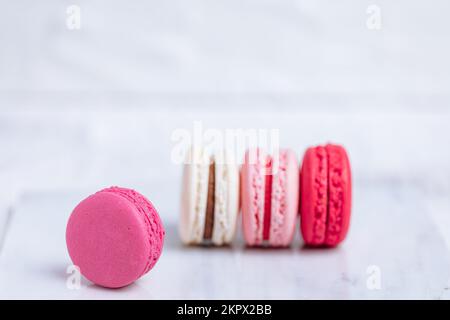 Close up of Macaroons in different colours on bright white background with subtle reflection on marble tray. Popular merengue dessert with filling ins Stock Photo