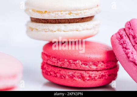 Close up of Macaroons in different colours on bright white background with subtle reflection on marble tray. Popular merengue dessert with filling ins Stock Photo