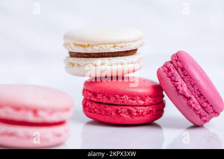 Close up of Macaroons in different colours on bright white background with subtle reflection on marble tray. Popular merengue dessert with filling ins Stock Photo