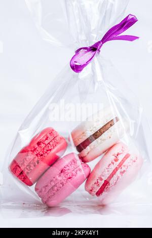 Close up of Macaroons in different colours on bright white background with subtle reflection on marble tray. Popular merengue dessert with filling ins Stock Photo