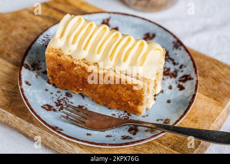 French dessert called Mille Feuille or Napoleon cake on rustic wooden board. Layered tasty cake with vanilla cream and puff pastry. Stock Photo